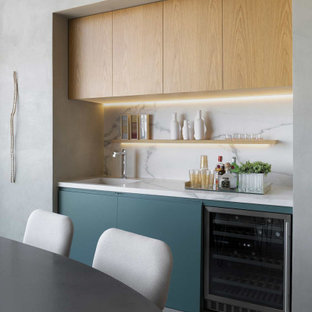 Idée de décoration pour un petit bar de salon avec évier linéaire design avec un évier intégré, un placard à porte plane, des portes de placard bleues, une crédence grise, un sol gris et un plan de travail gris.