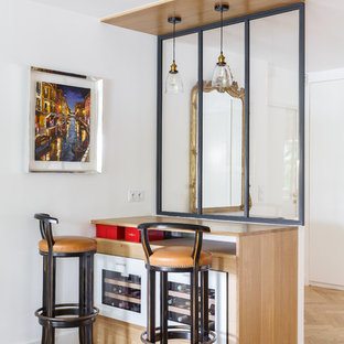Cette photo montre un petit bar de salon linéaire scandinave avec des tabourets, aucun évier ou lavabo, un plan de travail en bois, un sol en bois clair, un sol beige, un placard à porte vitrée, des portes de placard en bois clair et un plan de travail beige.