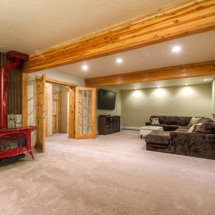 Exemple d'un grand sous-sol montagne enterré avec un mur beige, moquette et un poêle à bois.