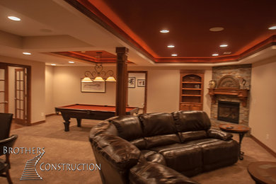 Inspiration for a mid-sized timeless underground carpeted basement remodel in Denver with beige walls, a standard fireplace and a stone fireplace