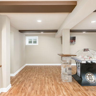 Example of a large mountain style look-out medium tone wood floor and beige floor basement design in Chicago with gray walls, a standard fireplace and a stone fireplace