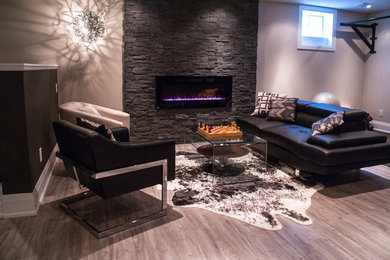 Mid-sized trendy underground basement photo in Toronto with gray walls, a standard fireplace and a stone fireplace
