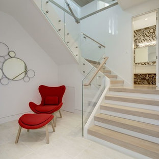 Cette photo montre un grand sous-sol tendance donnant sur l'extérieur avec un mur blanc, un sol en calcaire, une cheminée standard, un manteau de cheminée en pierre et un sol beige.