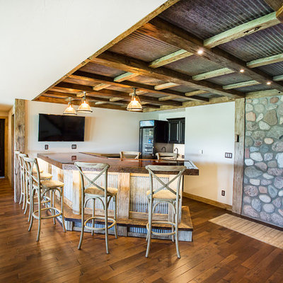 Example of a large mountain style walk-out dark wood floor basement design in Other with white walls, a standard fireplace and a stone fireplace
