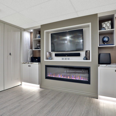 Example of a mid-sized trendy underground vinyl floor and gray floor basement design in Toronto with gray walls, a standard fireplace and a plaster fireplace
