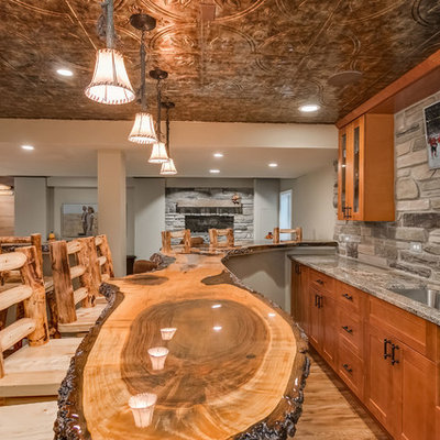 Basement - large rustic look-out medium tone wood floor and beige floor basement idea in Chicago with gray walls, a standard fireplace and a stone fireplace