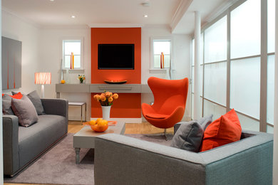 Modern inredning av ett vardagsrum, med orange väggar och mellanmörkt trägolv