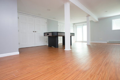 Example of a large trendy look-out light wood floor basement design in New York with gray walls and no fireplace