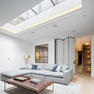 Inspiration for a medium sized contemporary fully buried basement in London with white walls, light hardwood flooring and beige floors.
