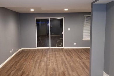 Inspiration for a mid-sized timeless walk-out medium tone wood floor and brown floor basement remodel in Chicago with gray walls and no fireplace