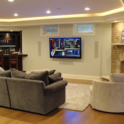 Inspiration for a large timeless look-out light wood floor basement remodel in Chicago with white walls, a standard fireplace and a brick fireplace