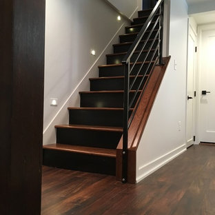 Idée de décoration pour un sous-sol minimaliste enterré et de taille moyenne avec un mur blanc, un sol en bois foncé, une cheminée standard, un manteau de cheminée en plâtre et un sol multicolore.