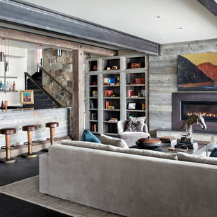 Idées déco pour un sous-sol montagne avec un mur beige, un manteau de cheminée en bois, une cheminée ribbon et un sol noir.