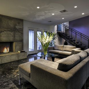 Aménagement d'un sous-sol contemporain donnant sur l'extérieur avec un mur violet, une cheminée standard, béton au sol et un manteau de cheminée en béton.