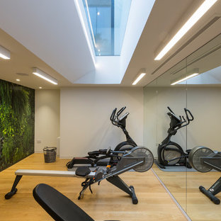 Medium sized contemporary basement in London with white walls, light hardwood flooring and beige floors.