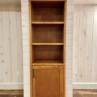 Aménagement d'un sous-sol craftsman donnant sur l'extérieur et de taille moyenne avec salle de jeu, un mur blanc, un sol en bois brun, une cheminée standard, un manteau de cheminée en pierre, un sol marron, un plafond en lambris de bois et du lambris de bois.