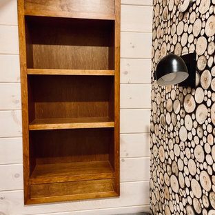 Aménagement d'un sous-sol craftsman donnant sur l'extérieur et de taille moyenne avec salle de jeu, un mur blanc, un sol en bois brun, une cheminée standard, un manteau de cheminée en pierre, un sol marron, un plafond en lambris de bois et du lambris de bois.