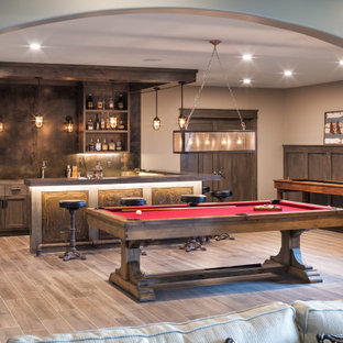 Cette image montre un très grand sous-sol chalet semi-enterré avec un mur gris, un sol en bois brun, un sol marron, boiseries et salle de jeu.