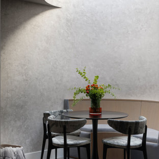 This is an example of a large contemporary fully buried basement in London with a home cinema, grey walls, light hardwood flooring and beige floors.