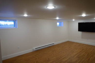 This is an example of a large basement in Portland Maine with medium hardwood flooring.