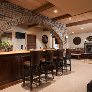 Esempio di una grande taverna tradizionale interrata con pareti beige, camino classico, cornice del camino in mattoni, pavimento con piastrelle in ceramica e pavimento beige