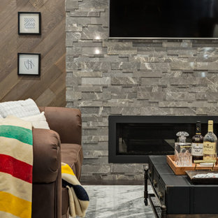 Idée de décoration pour un sous-sol design avec béton au sol, une cheminée standard, un manteau de cheminée en pierre de parement et un sol gris.