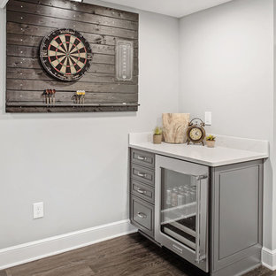 Réalisation d'un très grand sous-sol tradition semi-enterré avec un mur gris, un sol en vinyl, une cheminée standard, un manteau de cheminée en pierre et un sol gris.