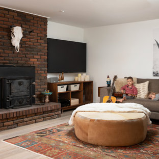 Photo of a modern walk-out basement in Denver with white walls, laminate floors, a wood stove and a brick fireplace surround.