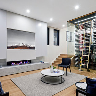 Inspiration for a contemporary look-out basement in Sydney with white walls, medium hardwood floors, a ribbon fireplace and brown floor.