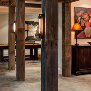 Idée de décoration pour un grand sous-sol chalet avec un mur beige, un sol en ardoise, aucune cheminée et un sol beige.