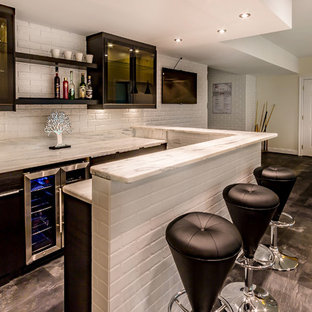 Aménagement d'un grand sous-sol moderne donnant sur l'extérieur avec un mur beige et un sol noir.