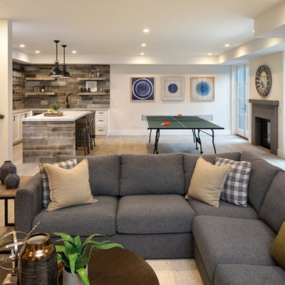 Inspiration for a large farmhouse walk-out ceramic tile and gray floor basement remodel in San Francisco with a stone fireplace, beige walls and a standard fireplace