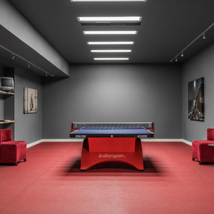 Aménagement d'un sous-sol moderne donnant sur l'extérieur et de taille moyenne avec un mur gris et un sol rouge.