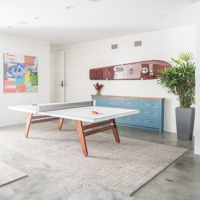 Example of a large beach style underground concrete floor and gray floor basement design in Orange County with white walls