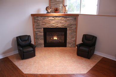 Mid-sized trendy underground dark wood floor basement photo in Ottawa with white walls, a standard fireplace and a stone fireplace