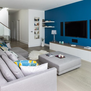 Inspiration for a large contemporary look-out basement in London with blue walls, medium hardwood flooring, no fireplace and brown floors.