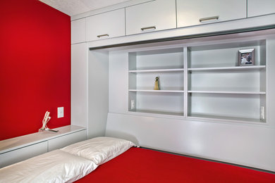 Foto de sótano con puerta contemporáneo de tamaño medio con paredes rojas, moqueta, estufa de leña, marco de chimenea de ladrillo y suelo gris