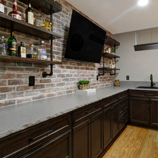 Idées déco pour un grand sous-sol montagne semi-enterré avec un mur beige, un sol en bambou, une cheminée ribbon, un manteau de cheminée en brique et un sol beige.