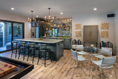 Inspiration for a large transitional walk-out vinyl floor and brown floor basement remodel in Atlanta with a bar, gray walls and no fireplace