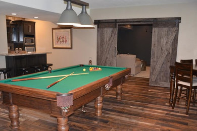 Example of a large transitional underground medium tone wood floor and brown floor basement game room design in Other with beige walls and no fireplace
