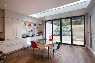 Medium sized contemporary walk-out basement in London with white walls, dark hardwood flooring and brown floors.
