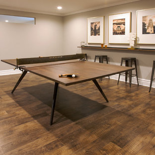 Idée de décoration pour un sous-sol tradition enterré avec un mur gris, un sol en vinyl, une cheminée double-face, un manteau de cheminée en bois et un sol marron.