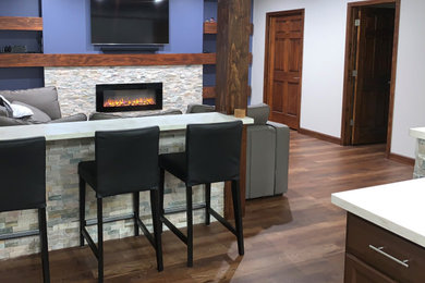 Example of a large transitional underground vinyl floor and brown floor basement design in Indianapolis with gray walls, a standard fireplace and a stone fireplace