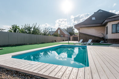 На фото: естественный, прямоугольный бассейн среднего размера на переднем дворе в современном стиле с домиком у бассейна и настилом с