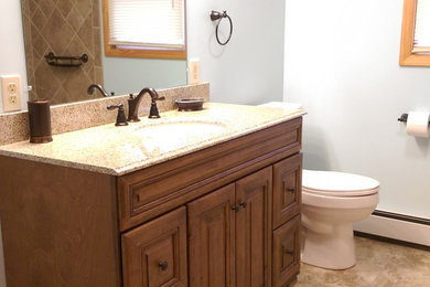 Example of a mid-sized classic master brown tile and porcelain tile vinyl floor bathroom design in Other with raised-panel cabinets, dark wood cabinets, a two-piece toilet, blue walls, an undermount sink and granite countertops