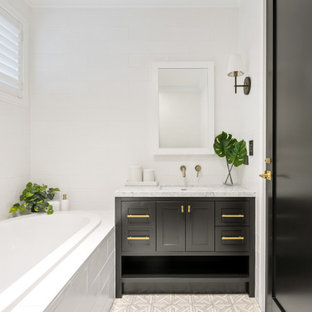 Photo of a country bathroom in Brisbane with shaker cabinets, black cabinets, a drop-in tub, white tile, white walls, an undermount sink, grey floor, grey benchtops, a single vanity and a built-in vanity.
