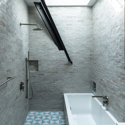 Mid-sized urban master gray tile and stone tile ceramic tile bathroom photo in New York with flat-panel cabinets, medium tone wood cabinets, a drop-in sink, solid surface countertops, a wall-mount toilet and gray walls