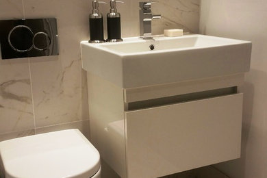 Imagen de cuarto de baño contemporáneo con sanitario de una pieza, paredes beige y lavabo suspendido