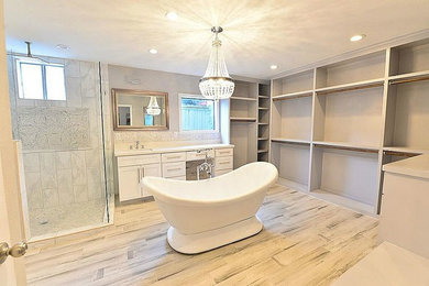 Inspiration for a medium sized classic ensuite bathroom in Houston with shaker cabinets, white cabinets, a freestanding bath, a corner shower, white tiles, stone tiles, grey walls, vinyl flooring, a submerged sink, quartz worktops, grey floors and a hinged door.