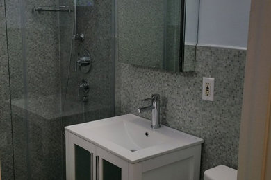 Cette image montre une petite salle de bain avec un placard à porte vitrée, des portes de placard blanches, WC séparés, un carrelage multicolore, des carreaux de céramique, un mur bleu, un sol en carrelage de porcelaine, un lavabo intégré, un sol noir et une cabine de douche à porte coulissante.